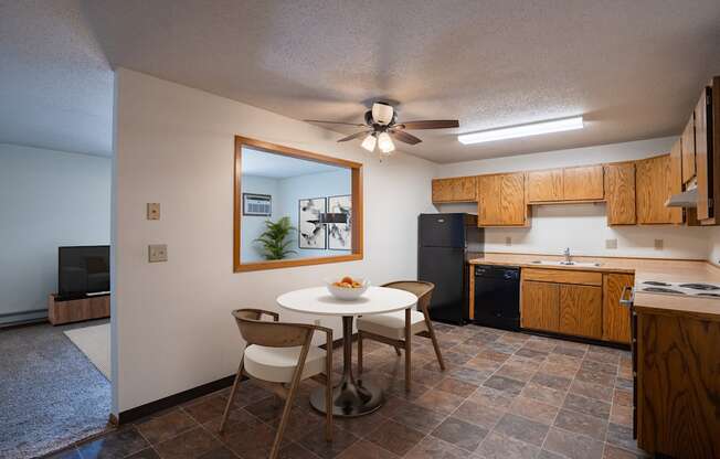 a kitchen and dining area with a white table and chairs. Fargo, ND Southview Village Apartments