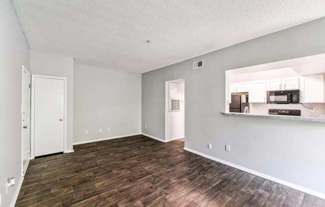 the living room and kitchen of an apartment with a hard wood floor