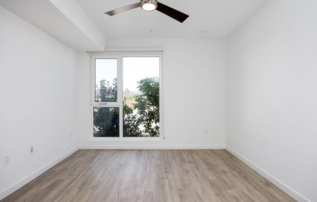 an empty living room with a ceiling fan and a window