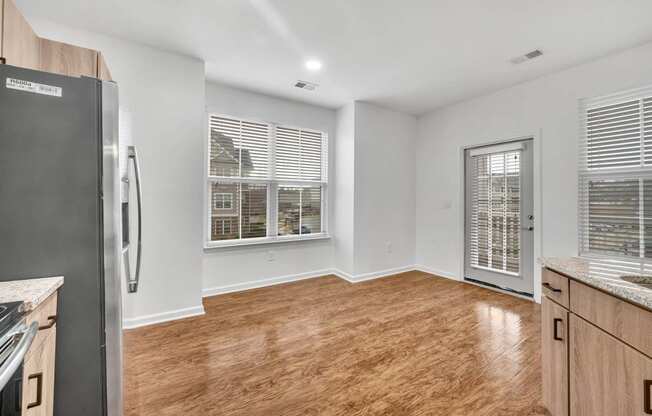 an empty kitchen and living room with a refrigerator and a window