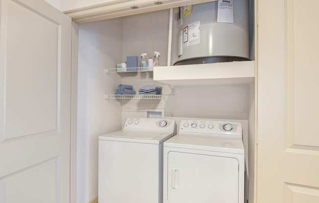 a small laundry room with a white washer and dryer and a shelf above