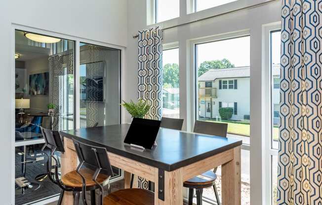 a dining area with a table and chairs and large windows