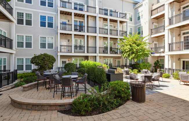 A courtyard with a table surrounded by chairs and plants.