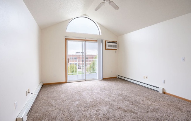 A room with a carpeted floor and a ceiling fan. Fargo, ND Summit Point Apartments