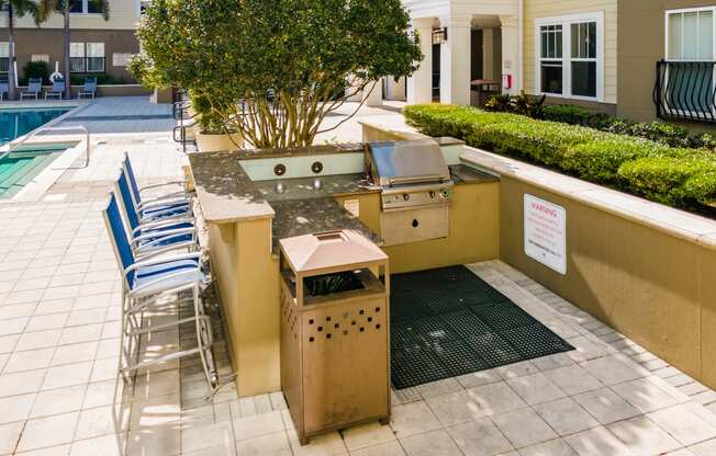 a barbecue grill in a backyard with chairs and a pool