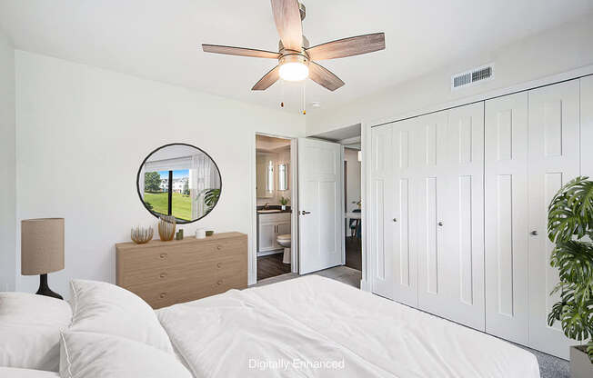 A bedroom with a bed, dresser, mirror, and a ceiling fan.