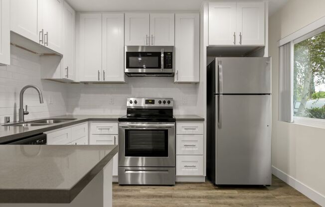 a kitchen with white cabinets and stainless steel appliances