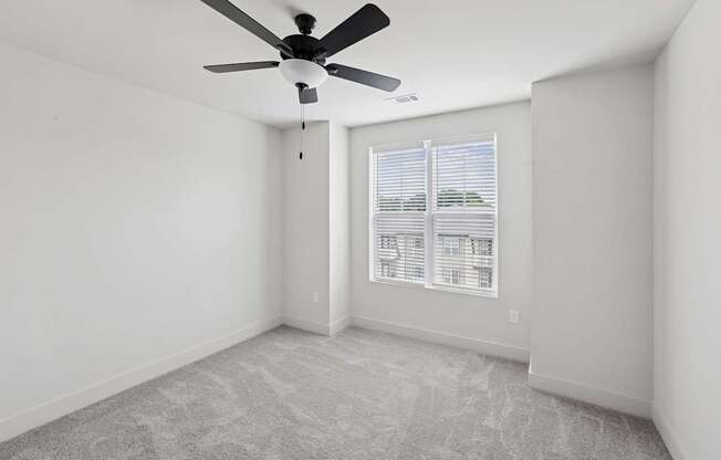 A room with a ceiling fan and carpeted floor.