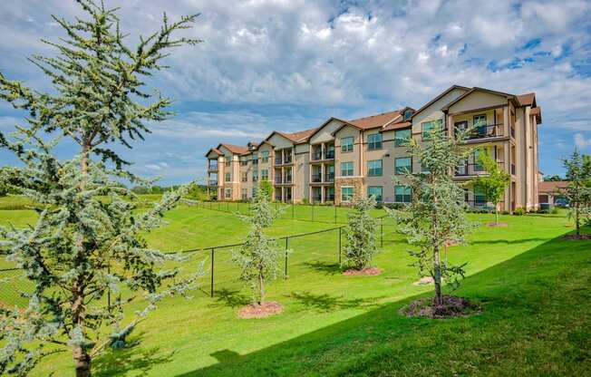 Exterior photo of Parc at Bentonville with trees and grass and building