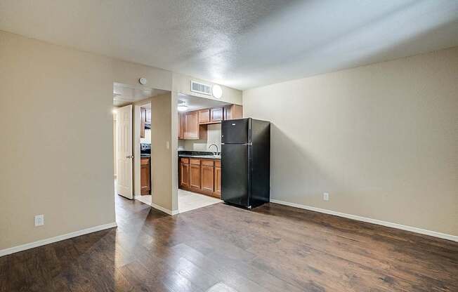 A kitchen with a black refrigerator and wooden floors.