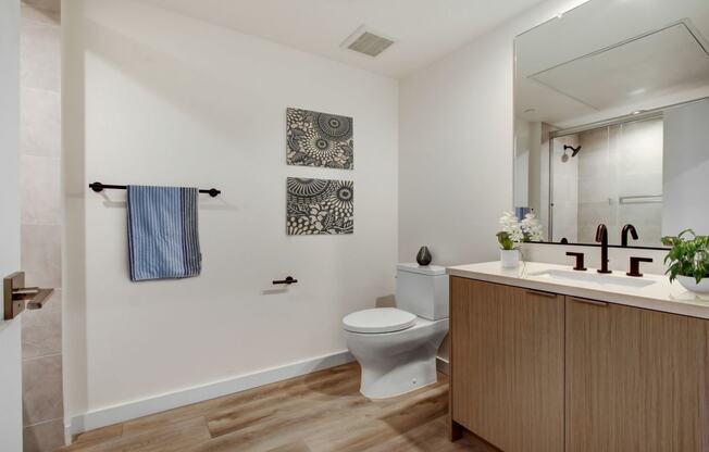 a bathroom with a toilet sink mirror and shower in a 555 waverly unit