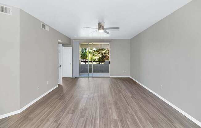 A room with a ceiling fan and a sliding glass door leading to a balcony.