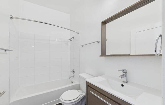 A white bathroom with a toilet, sink, and shower.