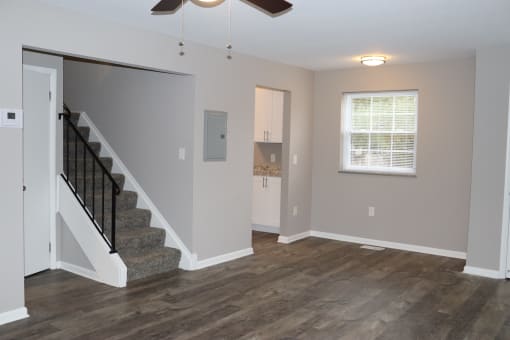 an empty living room with a staircase and a window