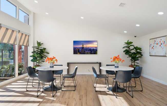 a room with tables and chairs and a large painting of a city on the wall