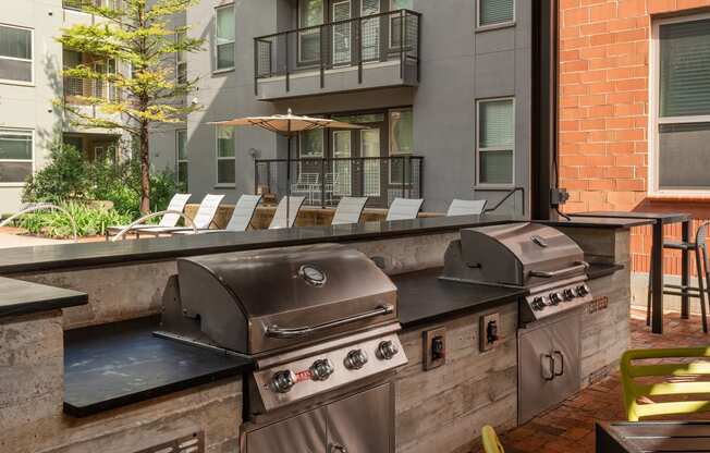 an outdoor grill area with chairs and stainless steel appliances