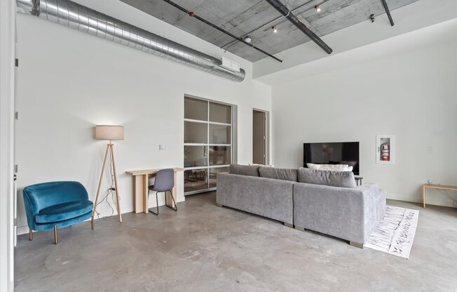 A living room with a grey couch, a blue chair, and a white floor lamp.