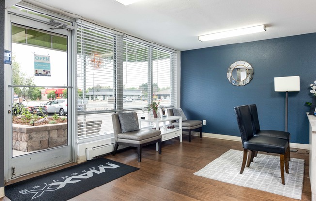 a living room with blue walls and a window with chairs and a table