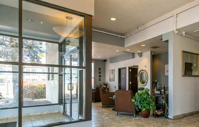 A glass door with a handle is open to a room with a chair and a potted plant.