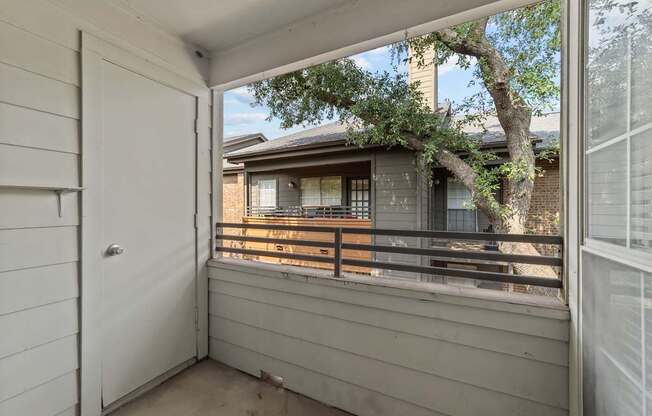 A view from a balcony looking at a house with a tree in the foreground.