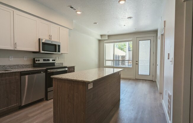 A kitchen with an island and a door leading to a balcony