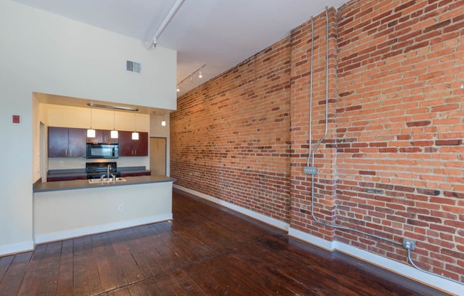 a living room with a brick wall and a kitchen at Mayton Transfer Lofts, Virginia