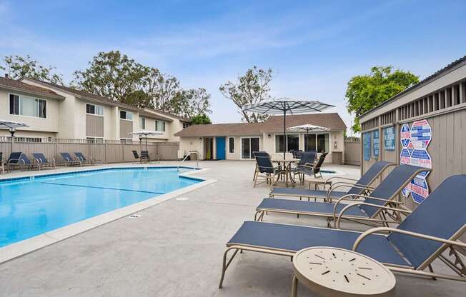 A pool with sun loungers and a building in the background.
