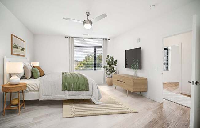 A bedroom with a bed, a side table, a dresser, and a ceiling fan.