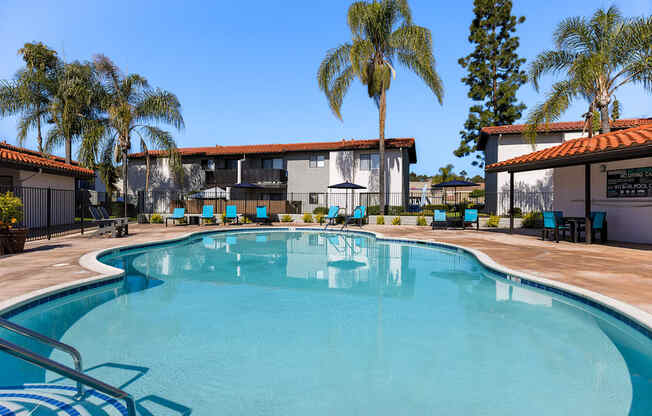A swimming pool surrounded by palm trees and a building.