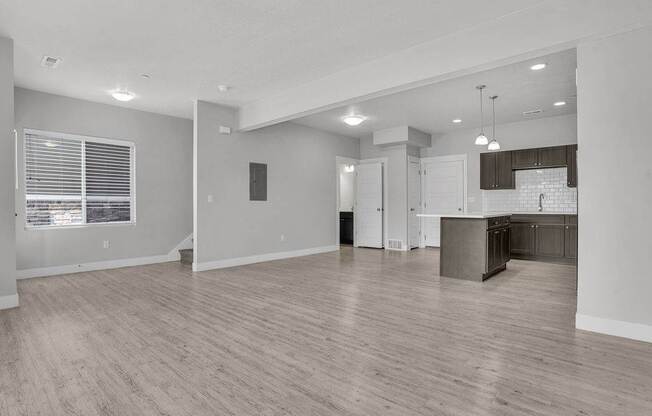 A spacious living room with a kitchen in the background.