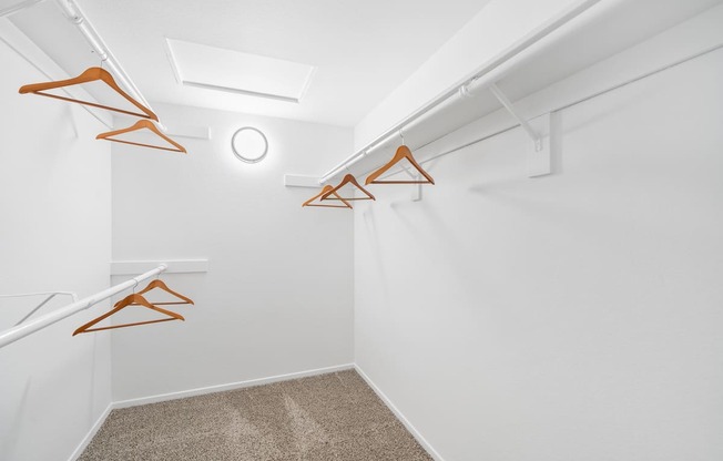 the interior of a white closet with white walls and orange hooks