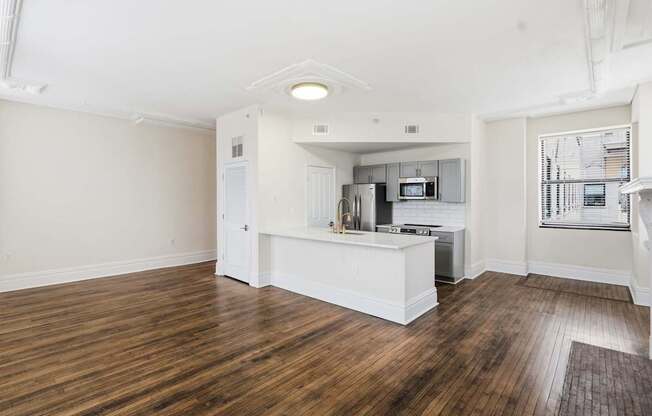 A kitchen with white cabinets and a wooden floor.
