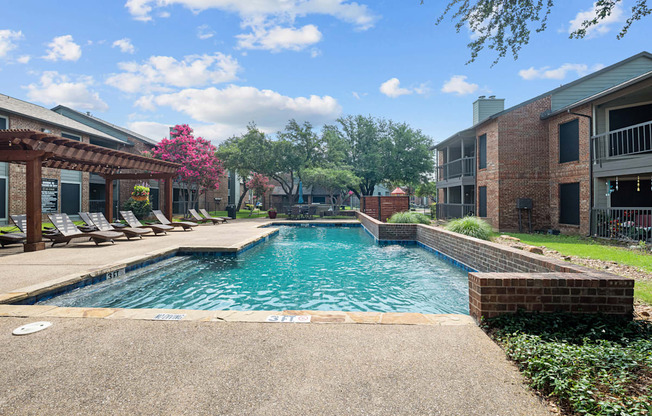 a swimming pool with lounge chairs and trees in the background