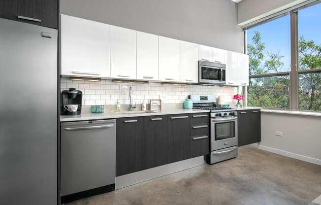 a kitchen with white cabinets and stainless steel appliances and a window