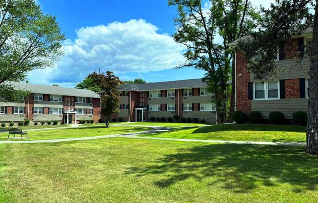 a grassy area with trees and buildings in the background