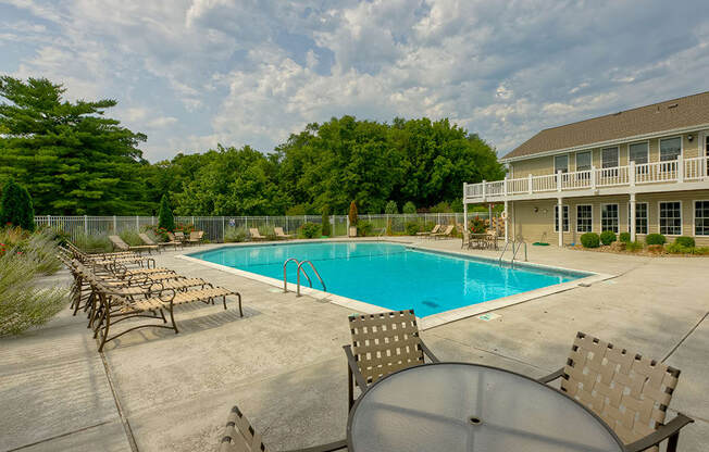 A pool surrounded by chairs and a table.
