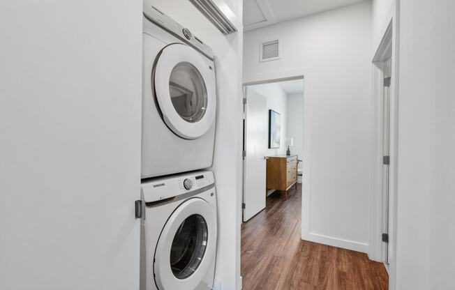 a white washer and dryer in a white laundry room with a wooden floor at Odyssey, Florida, 33905