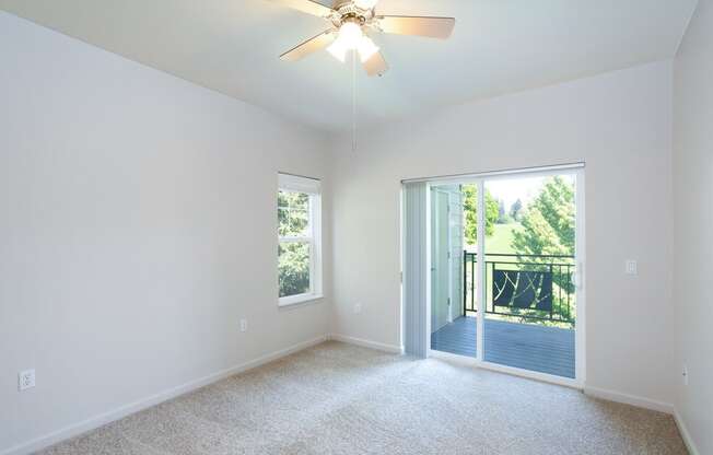 A room with a ceiling fan and sliding glass doors leading to a deck at Wilsonville Summit Apartments, Wilsonville 