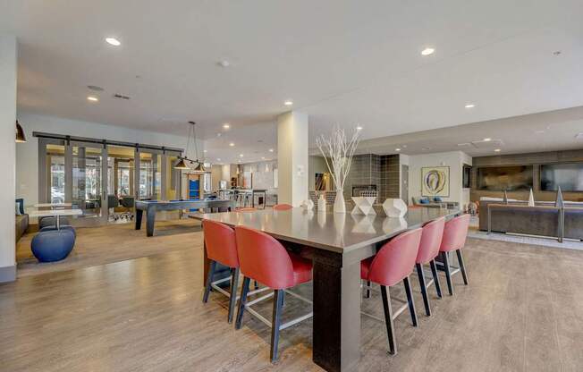 A modern kitchen with a long island and red chairs.
