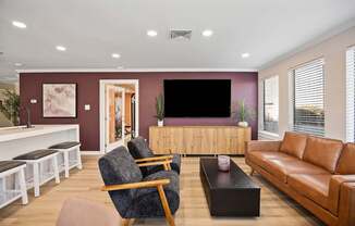 A living room with a grey armchair, a brown leather sofa, a wooden coffee table, and a white bench with black cushions.