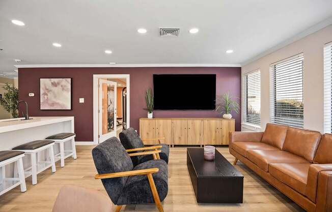 A living room with a grey armchair, a brown leather sofa, a wooden coffee table, and a white bench with black cushions.