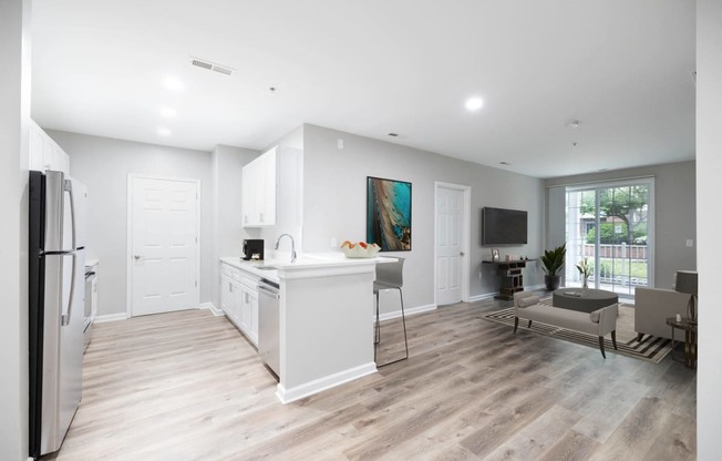 an open kitchen and living room with white walls and wood floors