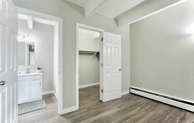 Bright and modern room featuring sleek floors, a spacious closet, and a stylish bathroom vanity, perfect for contemporary living.