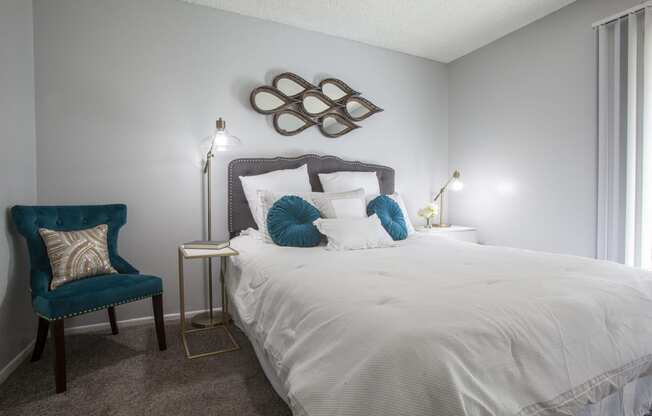 a bedroom with a white bed and a blue chair