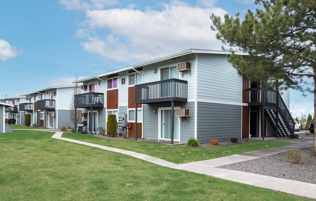 a row of town homes with a lawn and trees in front of them