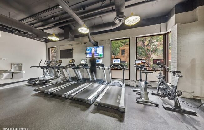 a gym with cardio equipment and windows in a building