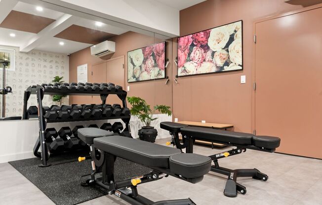 A gym room with a bench, weights, and a table.