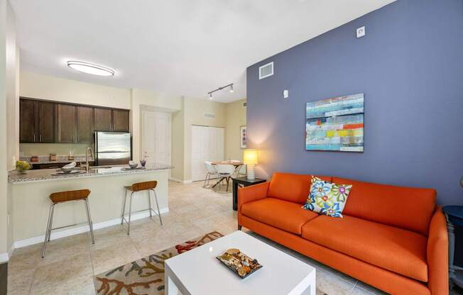 a living room with an orange couch and a kitchen with a bar