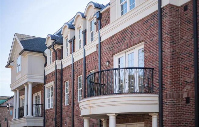 A red-brick building featuring arched balconies and white trim.