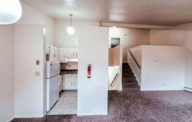 A kitchen area with a refrigerator, cabinets, and a stove top oven.